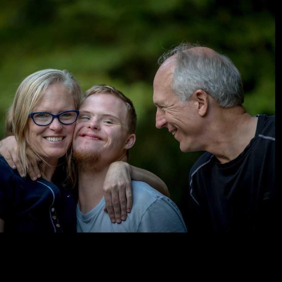 Eine glückliche Familie mit einem jungen Mann und seinen Eltern, die eng zusammenstehen.